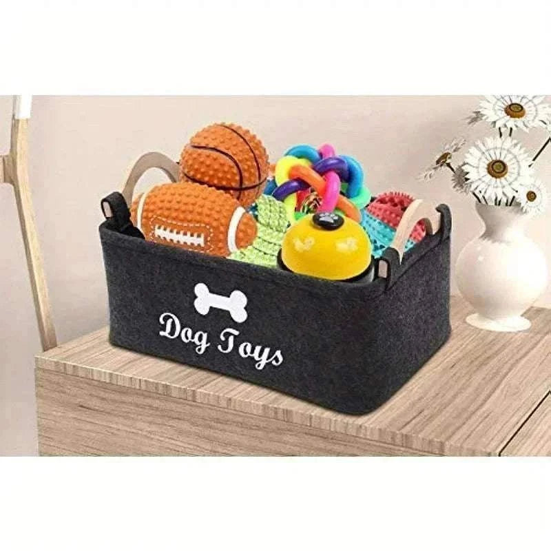 Panier de rangement en feutre noir avec poignées claires et inscription "Dog Toys", rempli de jouets colorés pour chiens, idéal pour organiser accessoires et jouets d’animaux.
